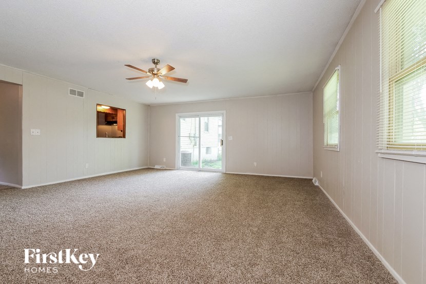 an empty living room with a ceiling fan and a window