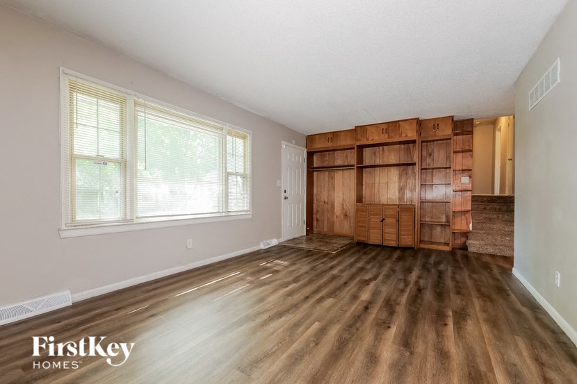 an empty living room with a large window and wood floors