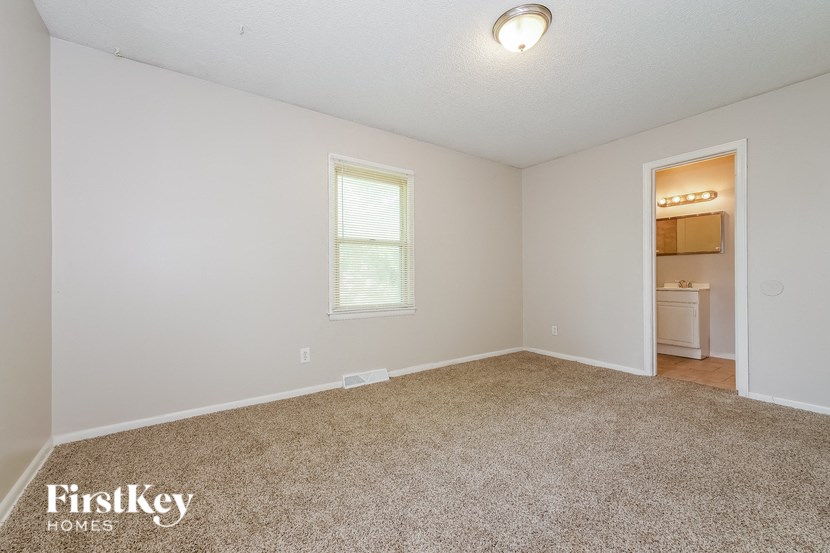 a bedroom with a carpeted floor and a door to a bathroom