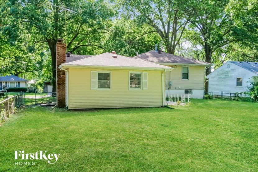 a small yellow house with a yard and trees