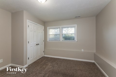 a bedroom with carpet and a door and a window