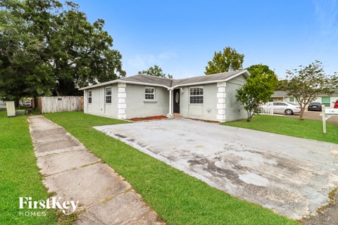 a small white house with a driveway and grass