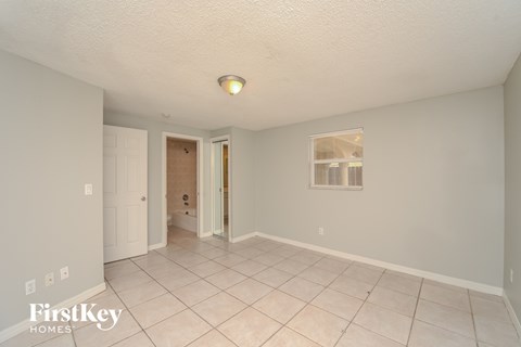 a living room with a tile floor and a door to a bathroom
