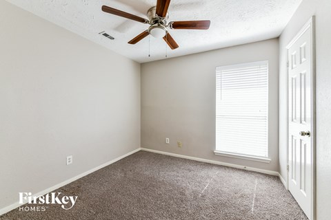 the bedroom has a ceiling fan and a carpeted floor