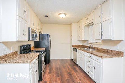 A kitchen with black appliances and white cabinets.