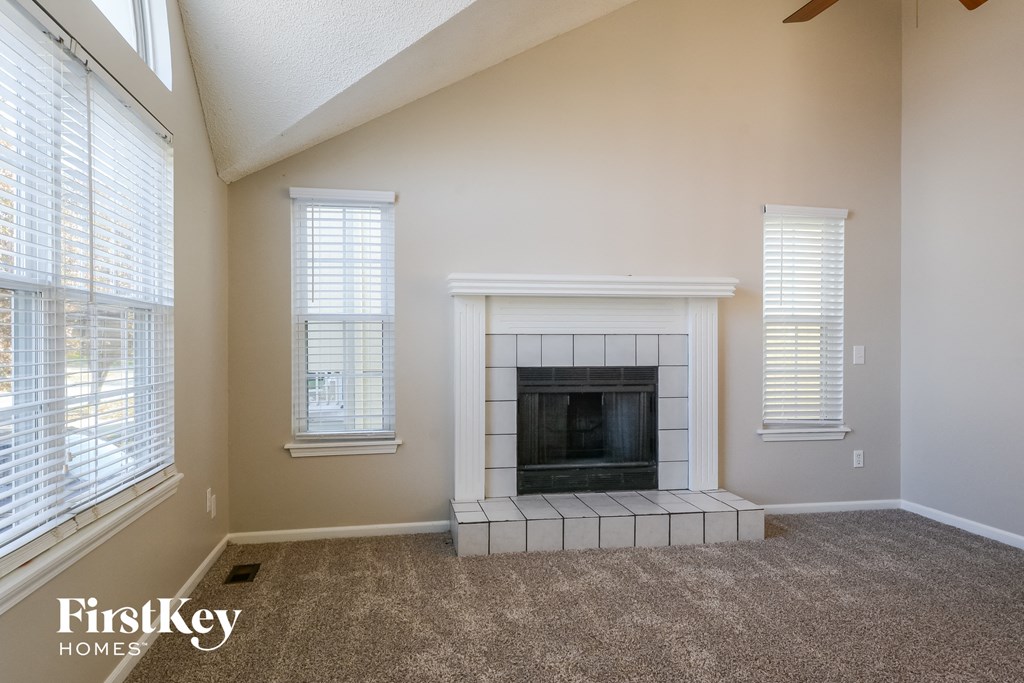 a living room with a fireplace and three windows