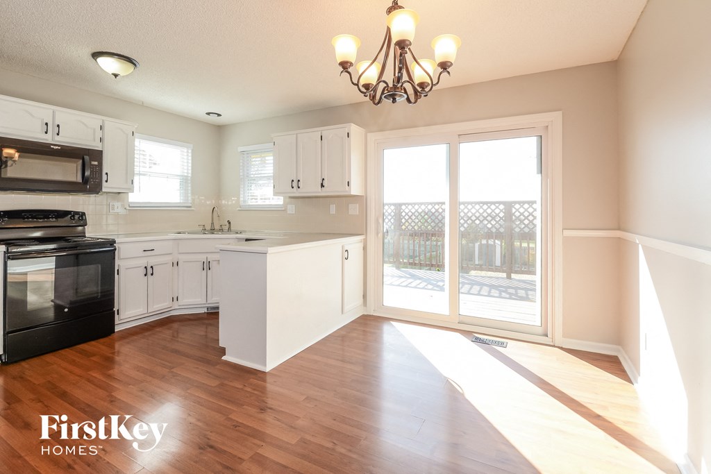 a kitchen with white cabinets and black appliances and a sliding glass door