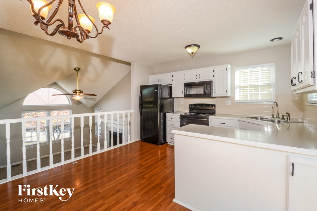 a kitchen with a white counter top and a black refrigerator