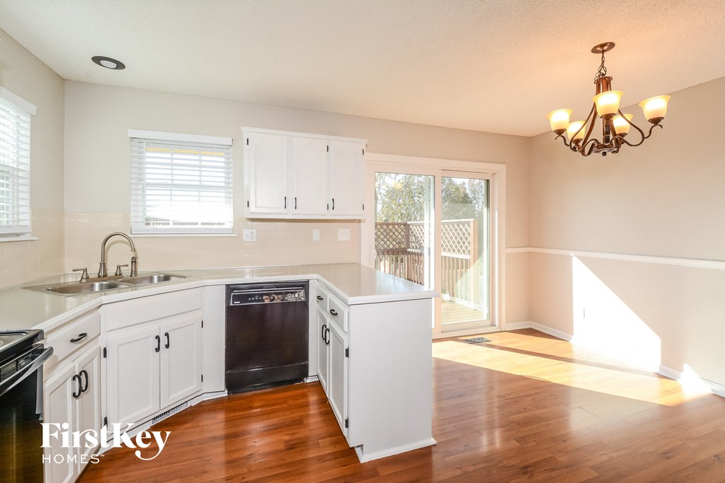 a kitchen with white cabinets and a dishwasher and a door to a balcony