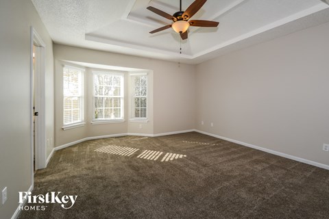a living room with carpet and a ceiling fan