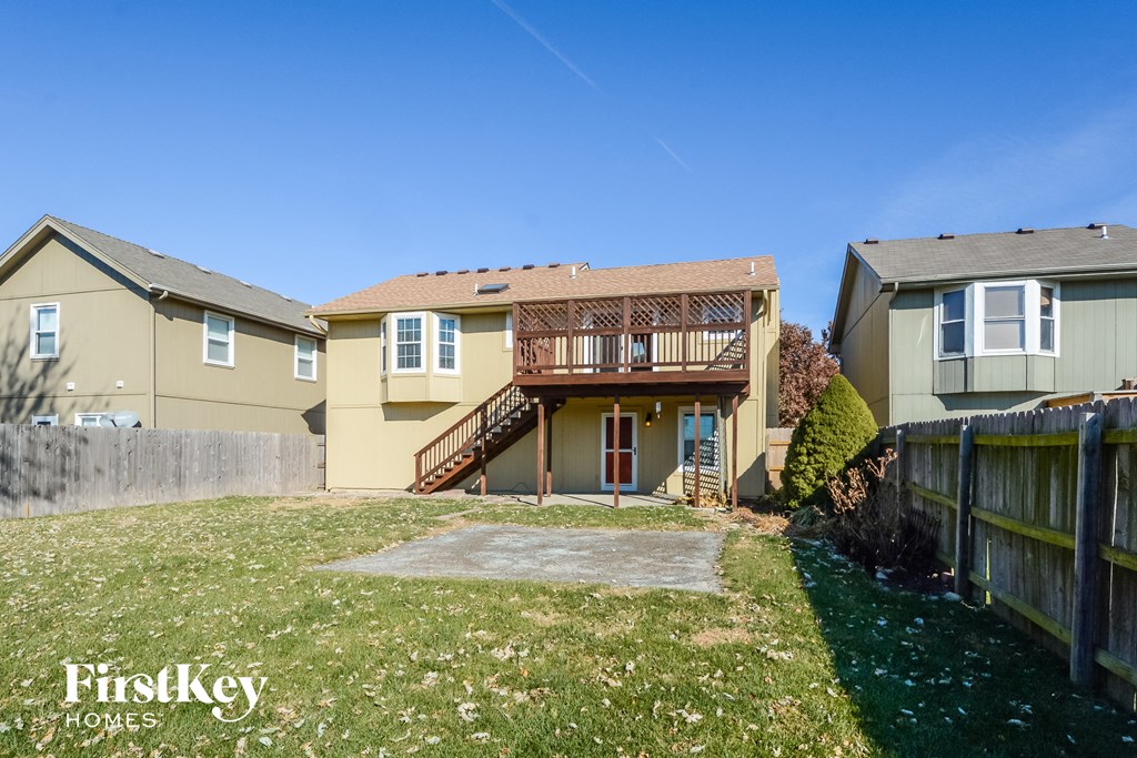 a backyard with a house with a deck and a fence