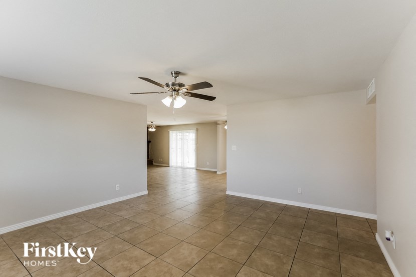 an empty living room with a ceiling fan and tiled floors