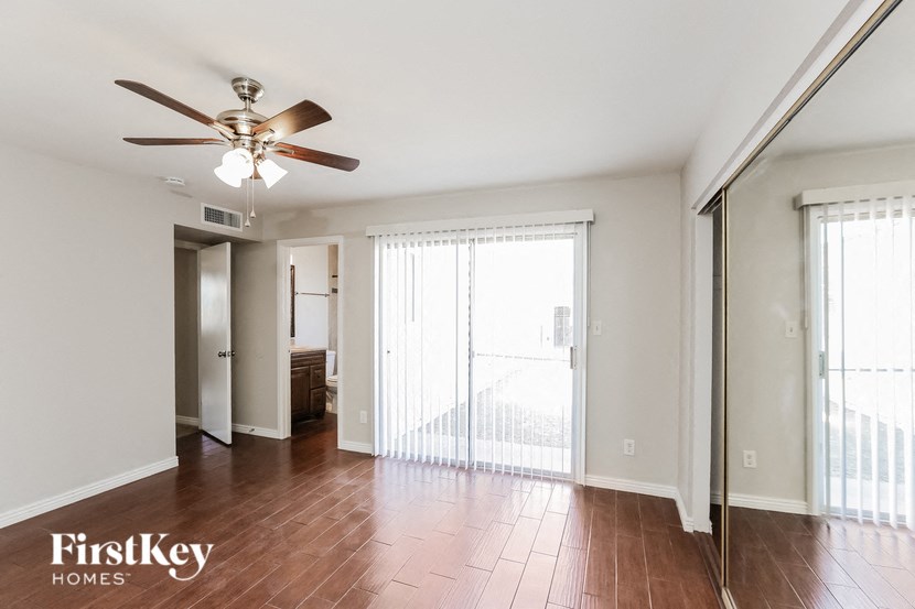 an empty living room with a ceiling fan and a large window