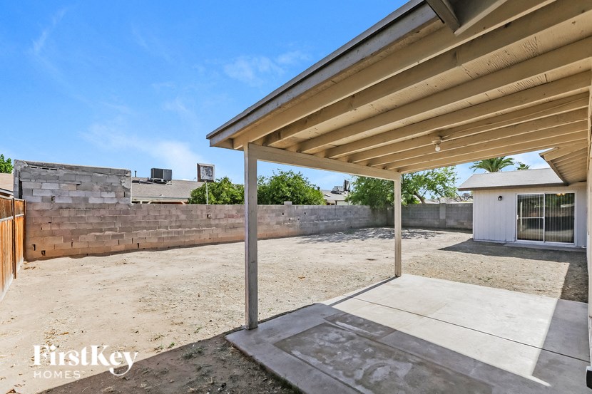 the backyard of a house with a patio and a retaining wall