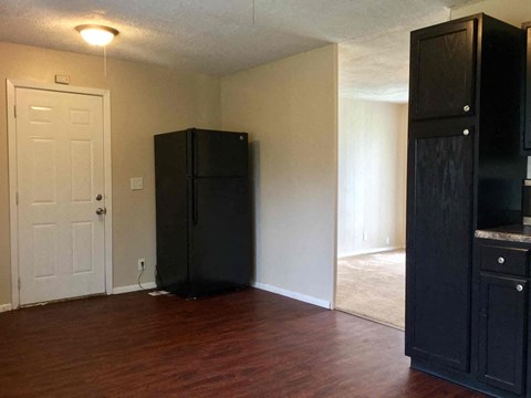 an empty living room with a refrigerator and a white door