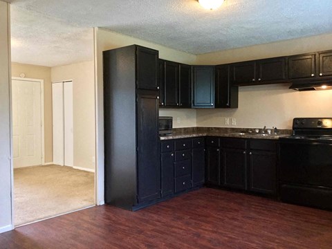 a kitchen with black cabinets and a wood floor