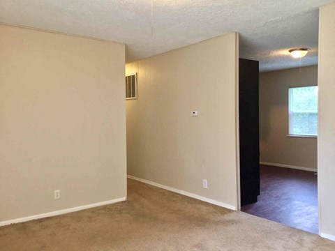 an empty living room with white walls and a window