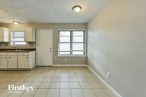 A kitchen area with a sink, cabinets, and a window.
