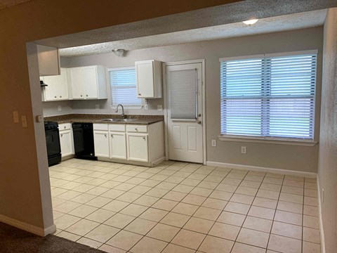A kitchen with white cabinets and a black dishwasher.