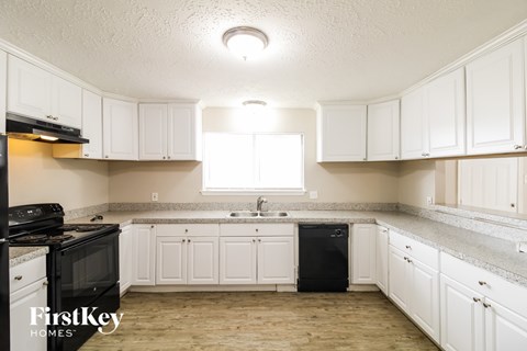 A kitchen with white cabinets and a black dishwasher.