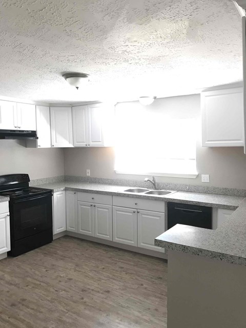 A kitchen with white cabinets and a black oven.