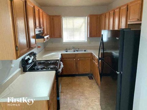 a kitchen with wooden cabinets and a black refrigerator