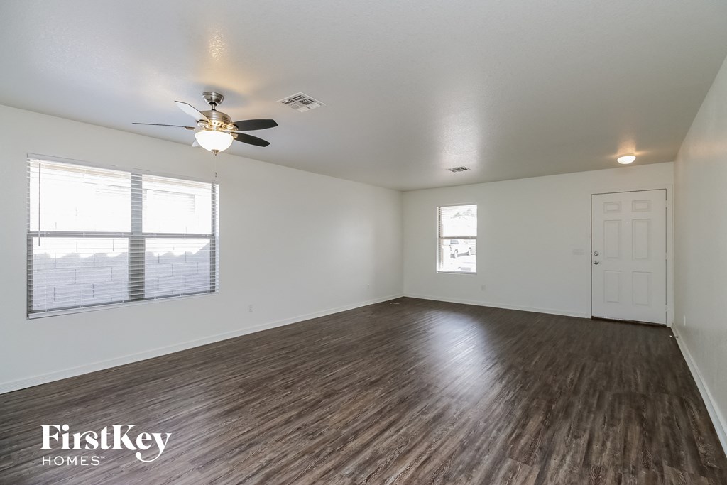 the living room of an empty house with a ceiling fan