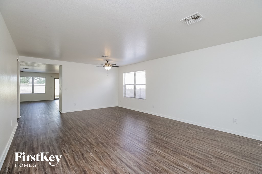 the living room and dining room of an empty house with wood flooring