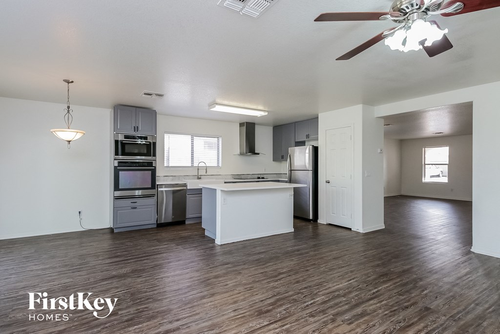 an empty kitchen with white cabinets and stainless steel appliances and a ceiling fan