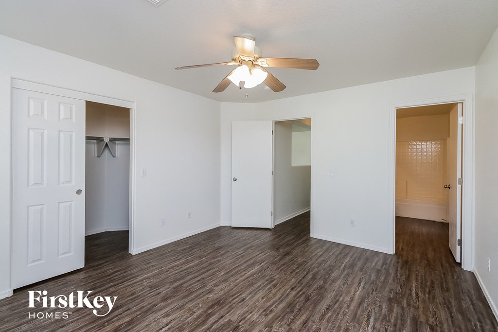 an empty living room with a ceiling fan and a closet