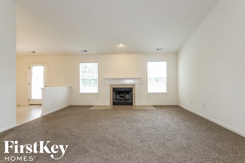 A spacious living room with a fireplace and carpeted floor.