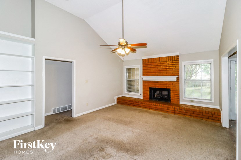 an empty living room with a fireplace and a ceiling fan