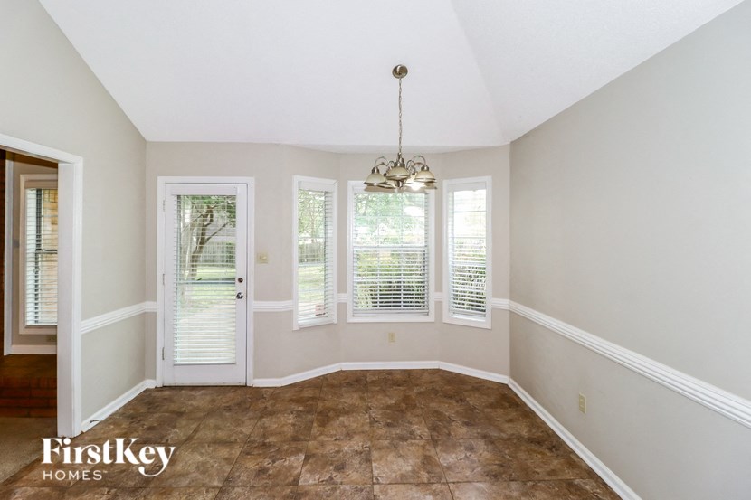 an empty dining room with windows and a chandelier