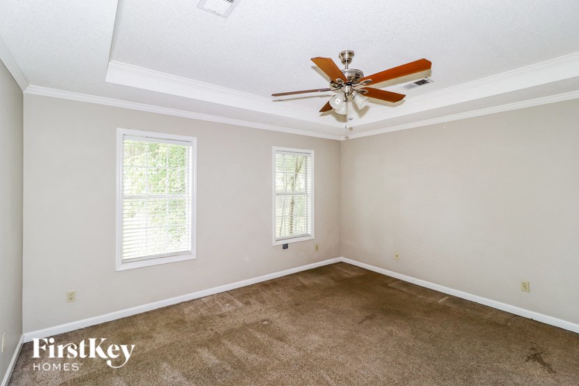 the living room of a home with carpet and a ceiling fan
