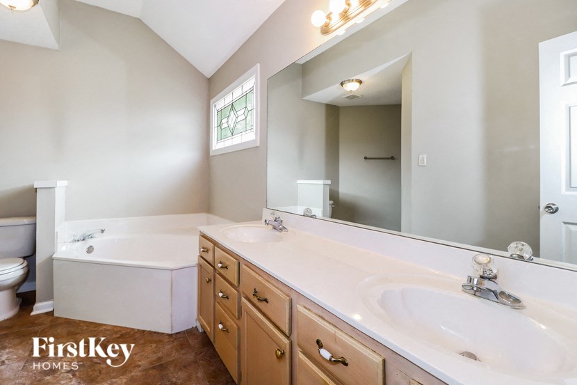 a bathroom with two sinks and a tub and a mirror