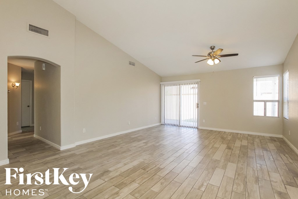the spacious living room with hardwood flooring and a ceiling fan