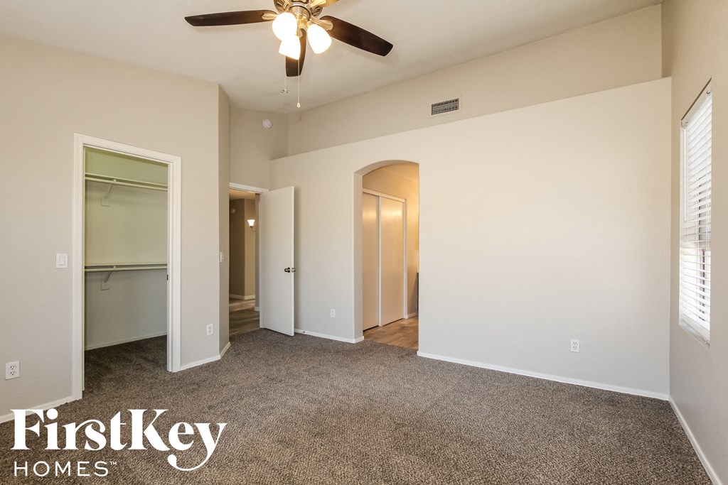 an empty living room with a ceiling fan and a closet