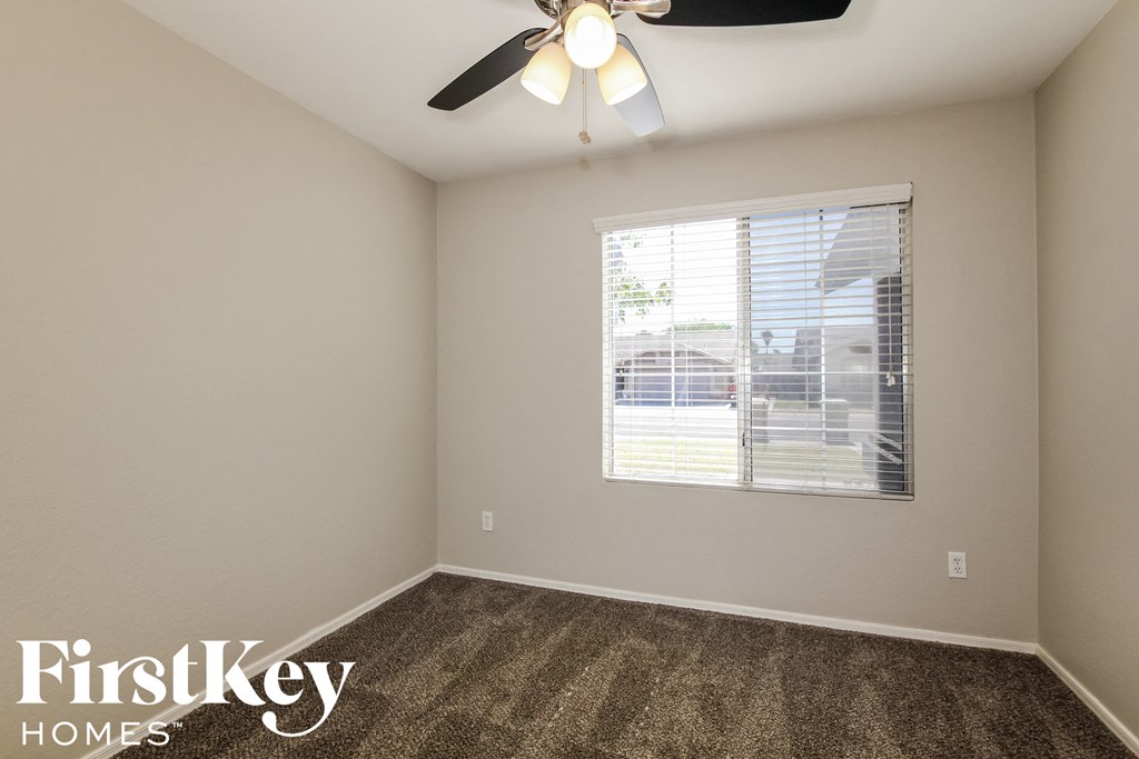 the living room of an apartment with carpet and a ceiling fan