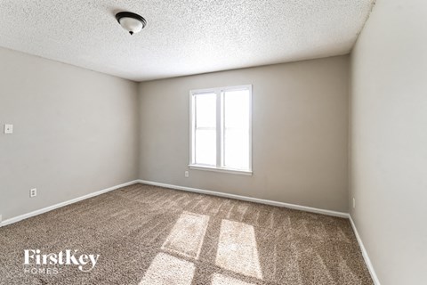the spacious living room of a house with carpet and a window