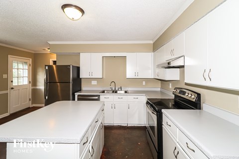 A kitchen with white cabinets and a black refrigerator.