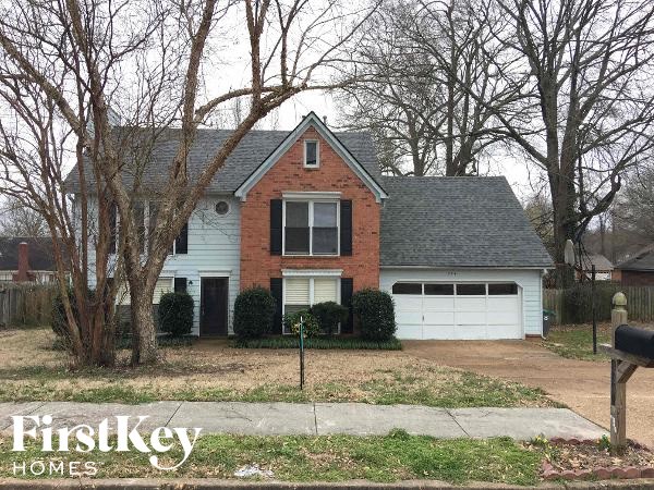 A brick house with a white garage door is for sale.