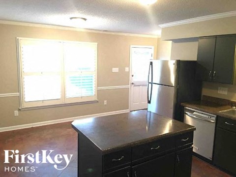 A kitchen with a black counter top and a refrigerator.