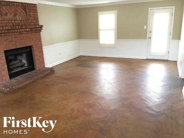 A room with a brick fireplace and wooden floors.