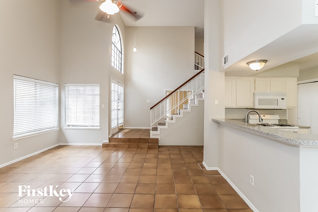an open kitchen and living room with a staircase and a window