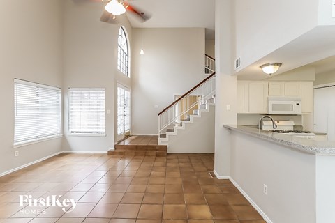an open kitchen and living room with a staircase and a window