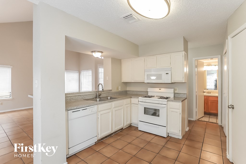 a kitchen with white cabinets and appliances and a sink