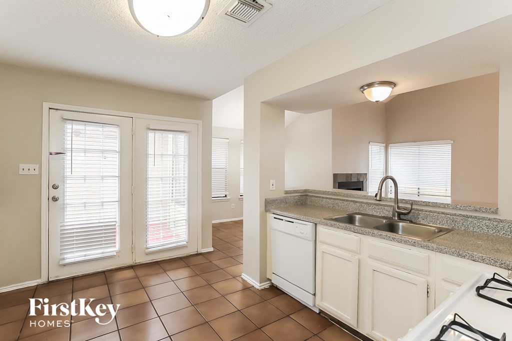 a kitchen with a sink and a door to a living room