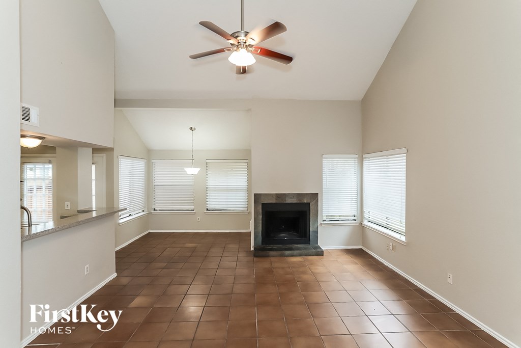 an empty living room with a fireplace and a ceiling fan