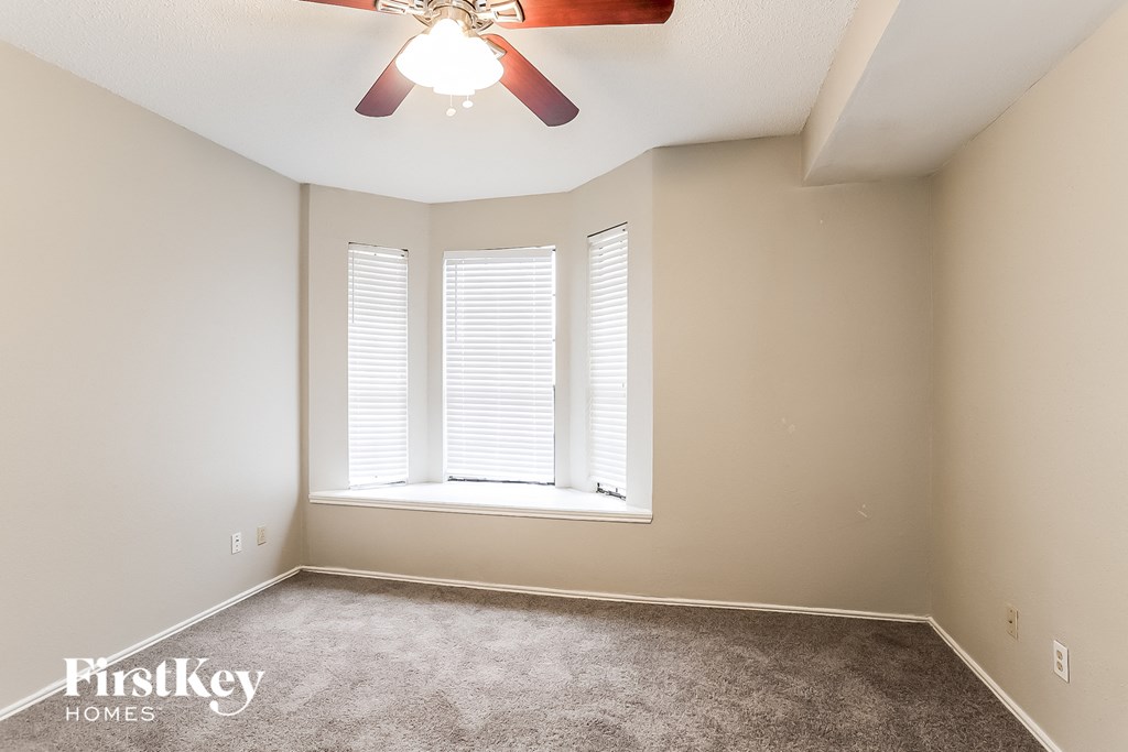 a bedroom with a large window and a ceiling fan