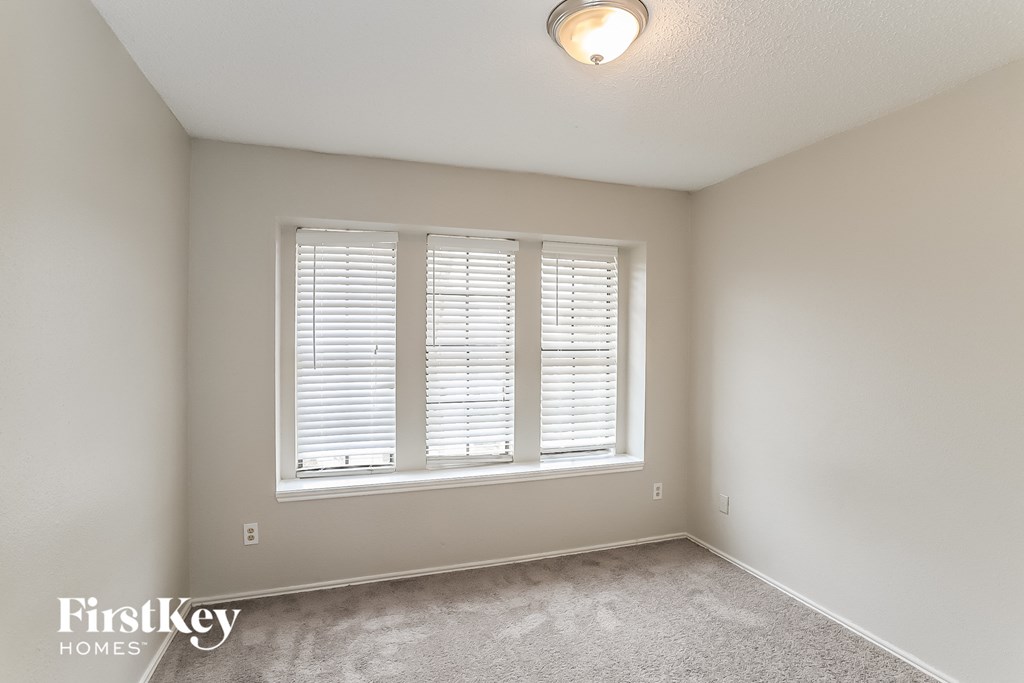 a bedroom with three windows and a carpeted floor